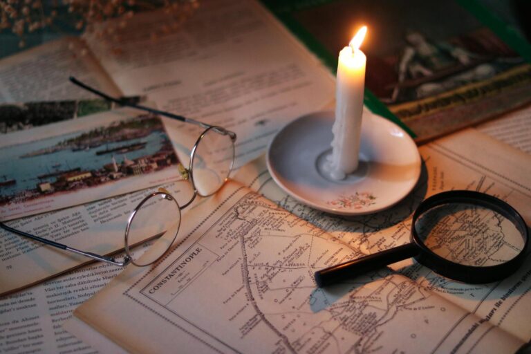 A hand tracing a vintage paper map by candlelight